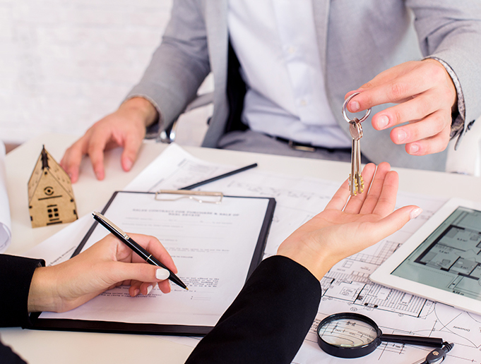 person giving a key to a person signing a contract